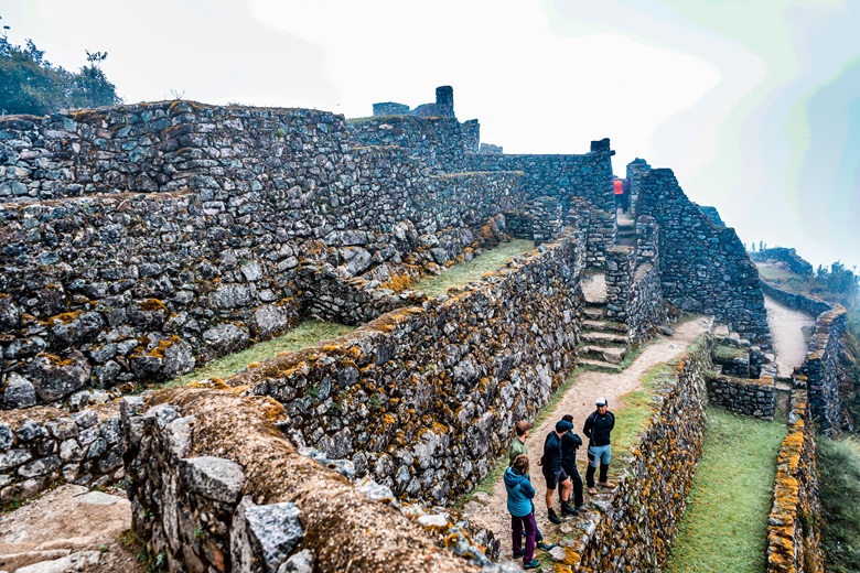 Hikers at the edge of stone Inca ruins